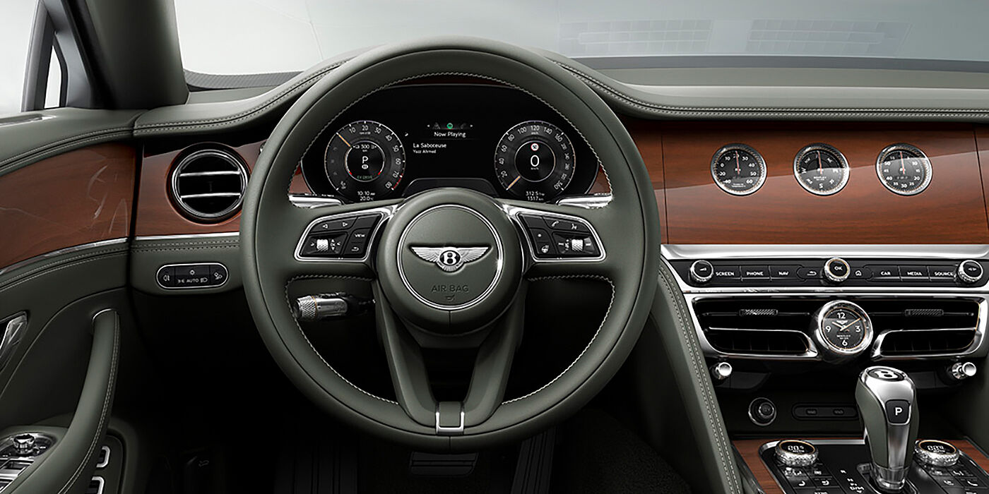 Bentley Kuwait New Bentley Flying Spur sedan front cabin in Cumbrian Green hide and Crown Cut walnut veneer showing steering wheel and Rotating Display with three clocks on face