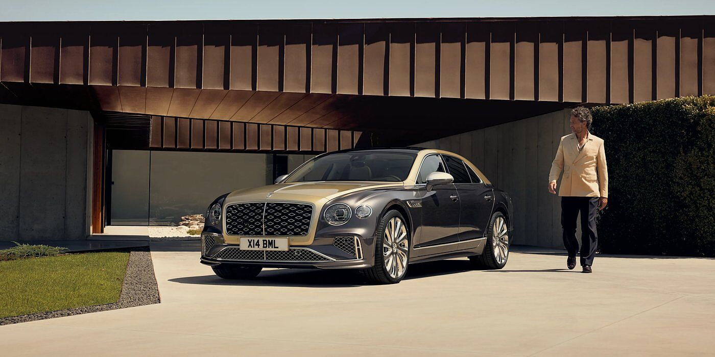 Bentley Kuwait Bentley New Flying Spur Mulliner V8 hybrid sedan front three quarters in Rose Gold over Magnetic paint, parked near modern home