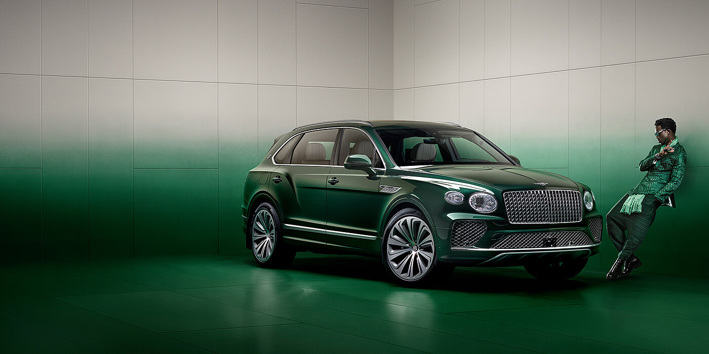 Bentley Kuwait Wisdom K leans against wall next to Bentley Bentayga Extended Wheelbase Atelier Edition SUV in Light Emerald green paint