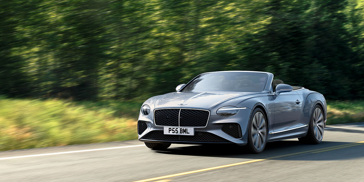 Bentley Kuwait New Bentley Continental GTC convertible front view in Silverlake paint with 22 inch ten spoke wheels, driving dynamically on a country road