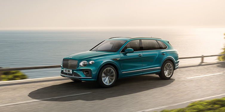 Bentley Kuwait Bentley Bentayga Extended Wheelbase Azure SUV in Topaz blue paint driving dynamically by the ocean