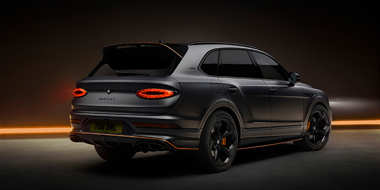 Bentley Kuwait Bentley Bentayga S Black Edition SUV rear three quarter in Anthracite Satin paint against a dark red and yellow background