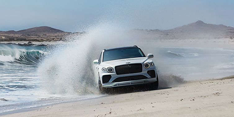 Bentley Kuwait Bentley Bentayga Speed SUV facing front in Snow Quarts Pearlescent white paint driving dynamically on beach