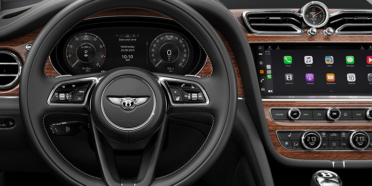 Bentley Kuwait Bentley Bentayga SUV front interior detail of steering wheel and driver screens surrounded by Beluga black hide and Crown Cut Walnut veneer