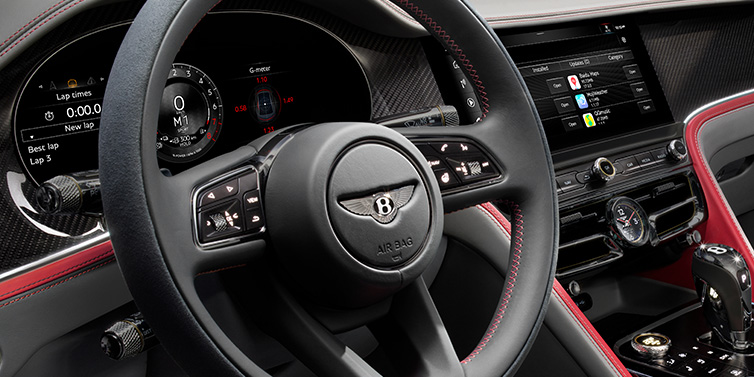 Bentley Kuwait Bentley Flying Spur Speed sedan front interior detail showing steering wheel and driver screens surrounded with Hotspur red and Gravity Grey hides